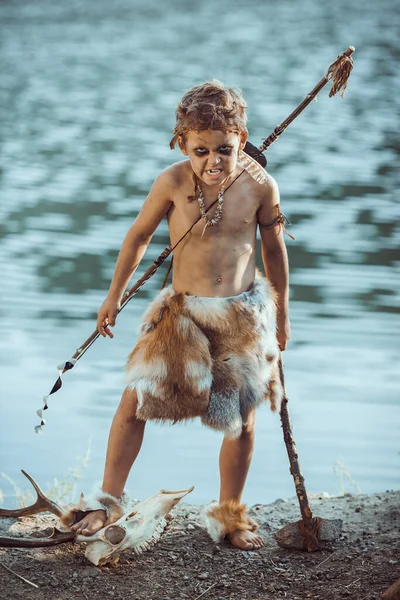 Cavernícola enojado, chico varonil con arma primitiva cazando al aire libre. Antiguo guerrero prehistórico. Mirada de película heroica —  Fotos de Stock