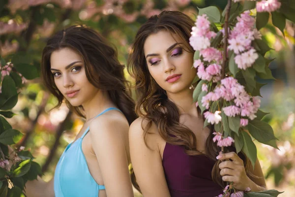 Foto de retrato de moda de dos mujeres cerca del árbol en flor en la naturaleza — Foto de Stock