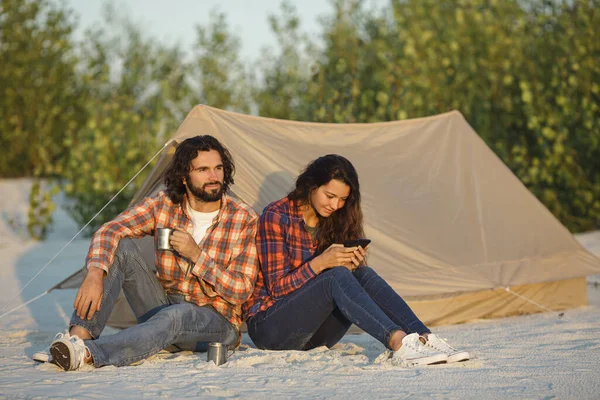 Couple heureux avec un smartphone dans le camp près de la tente En plein air — Photo