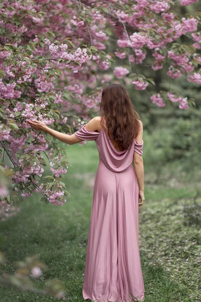 Frau am blühenden Sakura-Baum in der Natur — Stockfoto