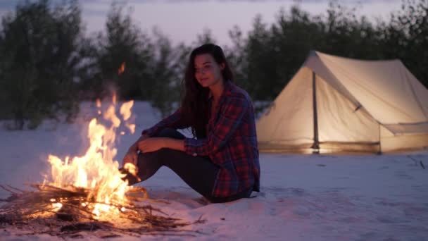 キャンプファイヤーの近くのキャンプで観光客の女性 — ストック動画
