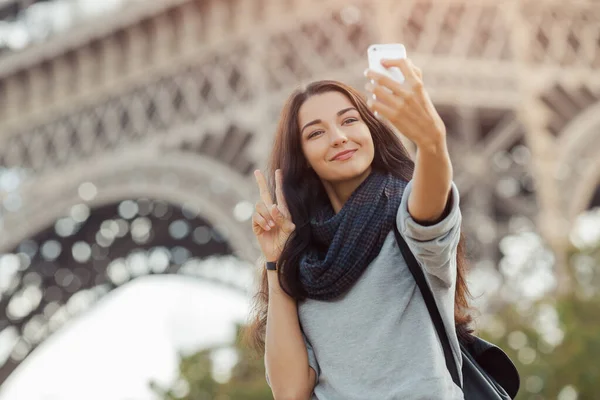 Gyönyörű fiatal lány vicces szelfit készít mobiltelefonjával az Eiffel-torony közelében. — Stock Fotó