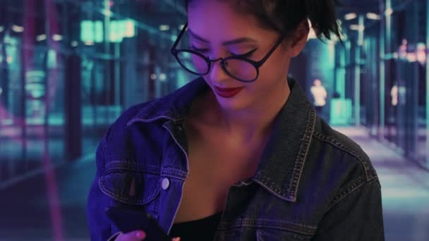 Kvinna som använder en smartphone i staden på natten — Stockvideo