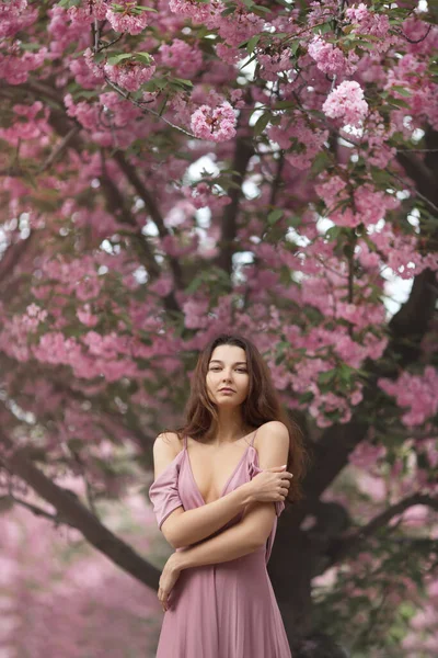 Frau am blühenden Sakura-Baum in der Natur — Stockfoto