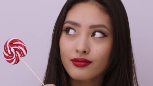 Модный портрет азиатки с леденцом в студии — стоковое видео