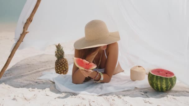 Γυναίκα στην τροπική παραλία τρώει καρπούζι — Αρχείο Βίντεο