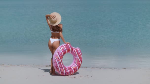 Žena na pláži s gumovým kroužkem. — Stock video