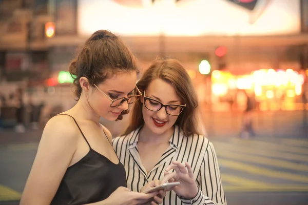 Mujeres en la ciudad usando un teléfono — Foto de Stock