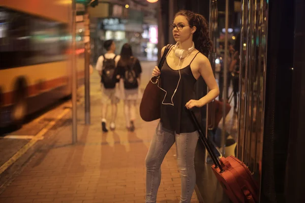 Ung kvinna väntar vid busshållplatsen — Stockfoto