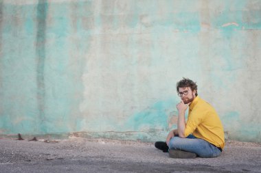 adam mavi bir duvarın önünde oturuyor