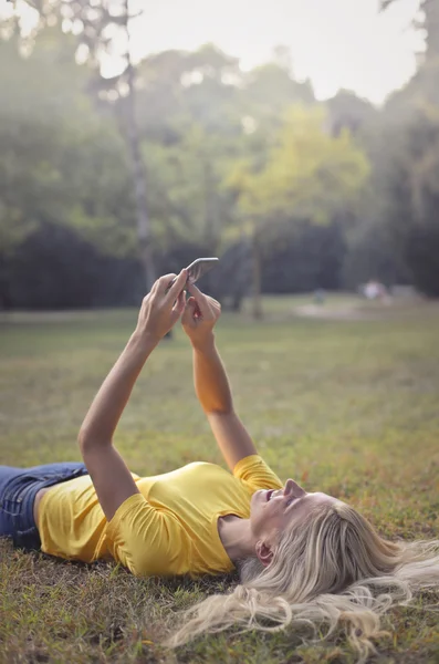 女人正在使用她的手机，在公园里 — 图库照片