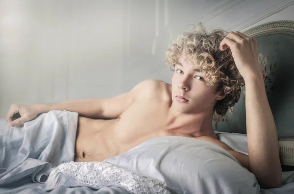 A fiatalember layingon ágy — Stock Fotó