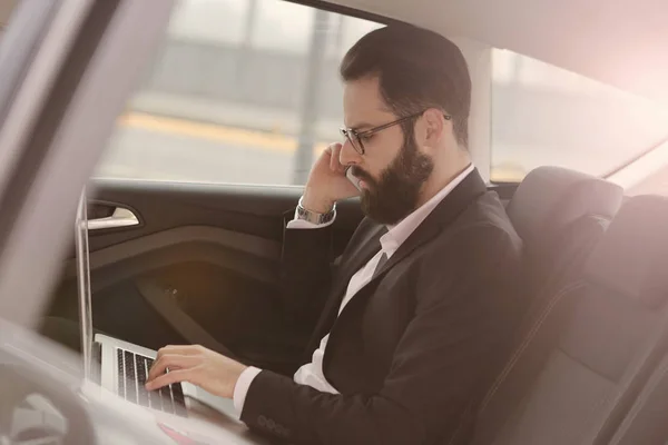 Empresario usando el ordenador portátil en el coche — Foto de Stock