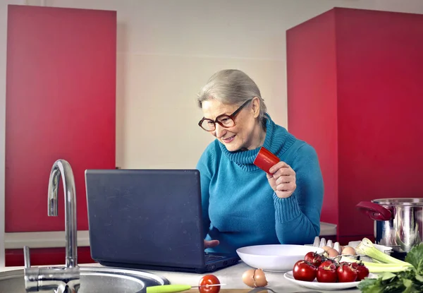 Főzés a laptop az öreg hölgy — Stock Fotó