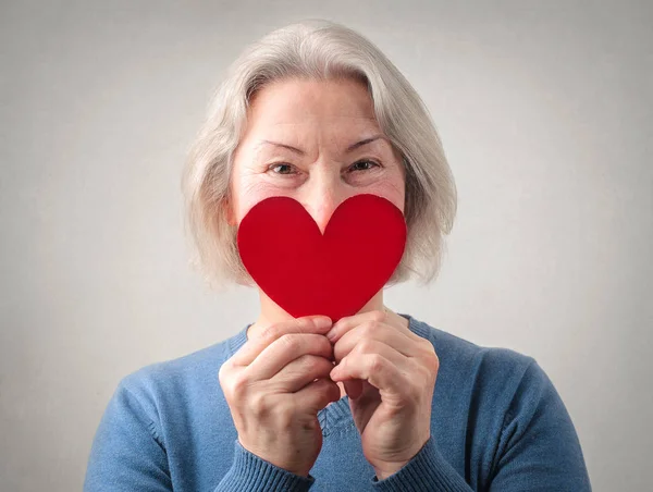 Señora mayor sosteniendo un corazón rojo —  Fotos de Stock