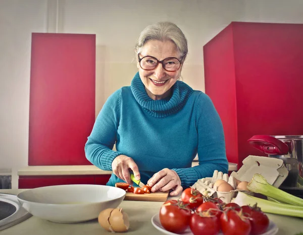 Older lady cutting vegetables — Stock Photo, Image