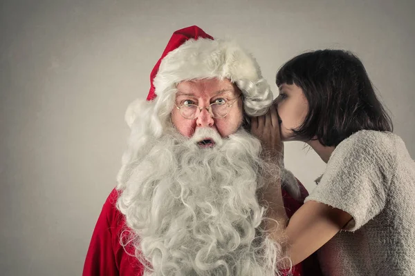 Frau flüstert Weihnachtsmann zu — Stockfoto