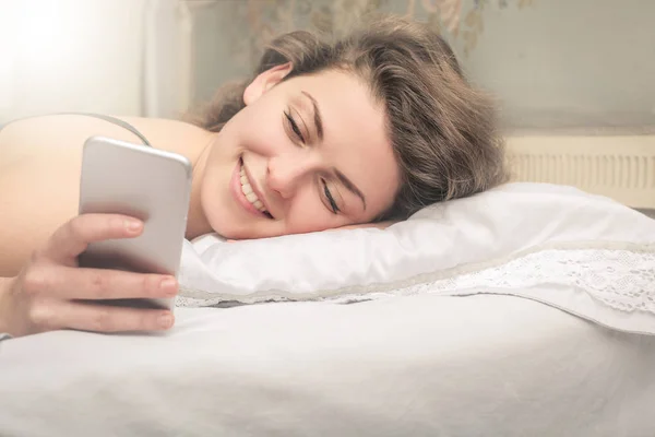 Frau im Bett mit Telefon — Stockfoto