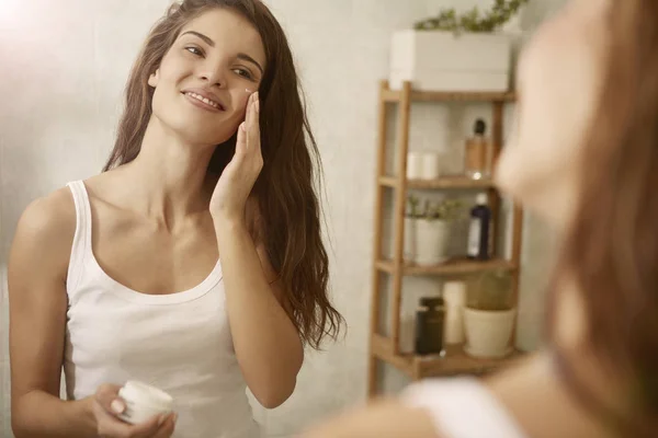 Femme utilisant une crème sur son visage — Photo