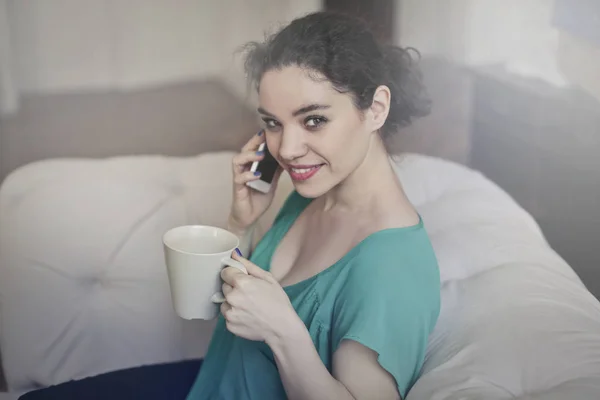 若い女性は、電話とお茶を飲みながら — ストック写真