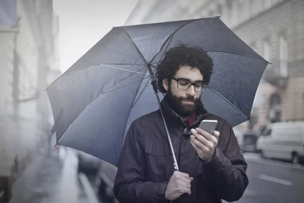 Mann mit Regenschirm spazieren — Stockfoto