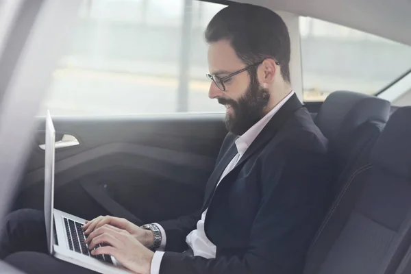 Businessman with laptop in car — Stock Photo, Image