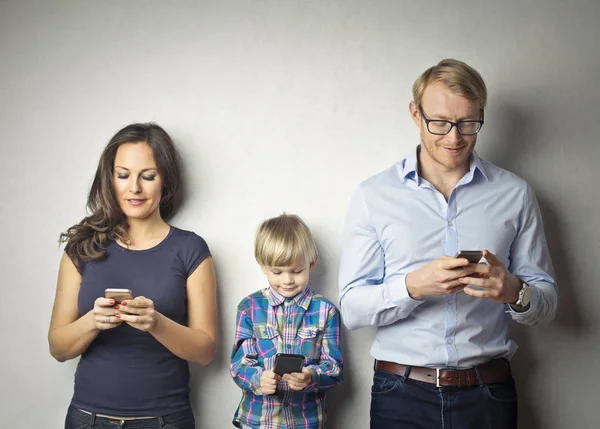 Pais e filhos usando telefones inteligentes — Fotografia de Stock