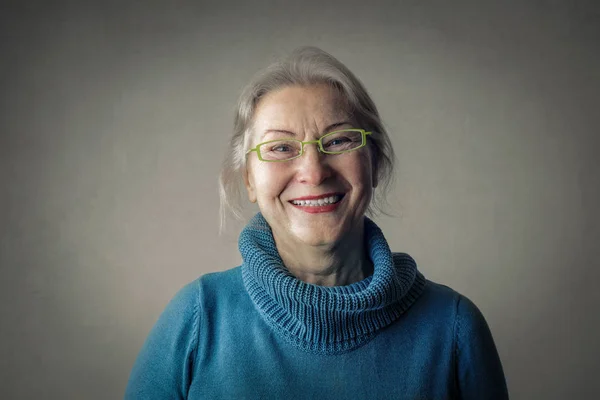 Stará dáma v brýlích s úsměvem uvnitř — Stock fotografie