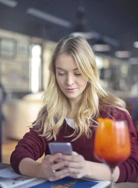 Blond kvinna tittar på hennes telefon — Stockfoto