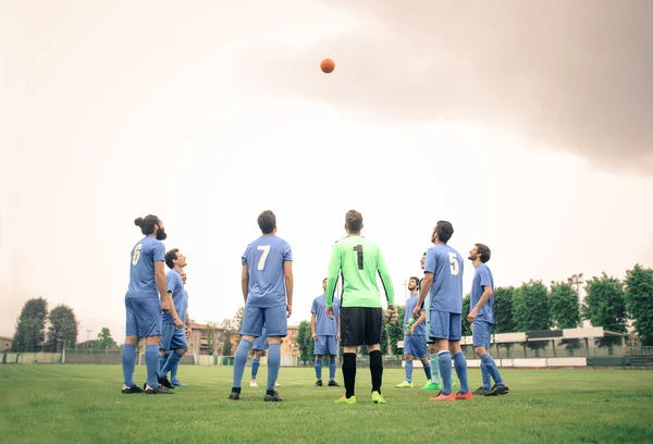 Jogadores de futebol olhando para bola voadora — Fotografia de Stock