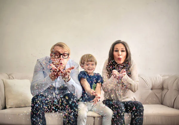 Parents et garçon soufflant des confettis à l'intérieur — Photo