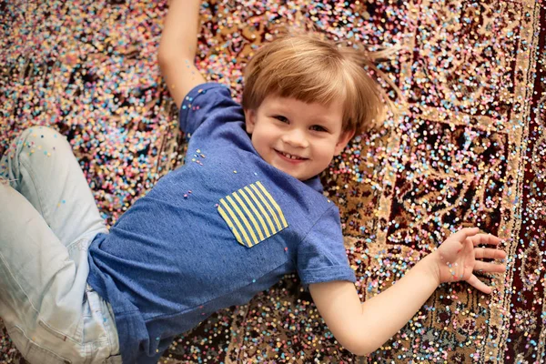 Boy laying in confetti — Stock Photo, Image