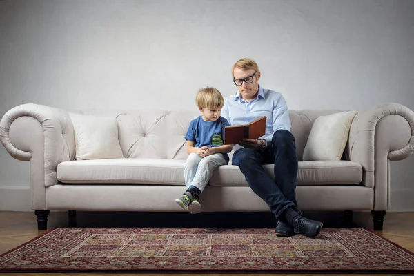 ソファの上の男の子と読むお父さん — ストック写真