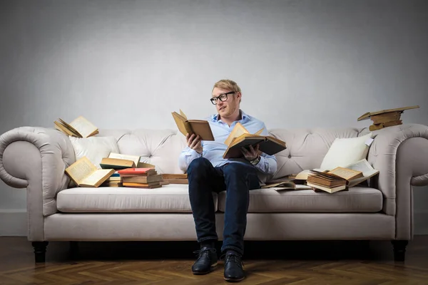 Hombre con gafas leyendo en el sofá — Foto de Stock