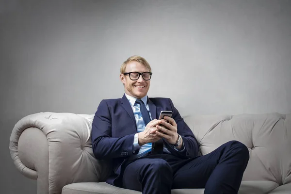 Biznesmen z telefonu, siedząc na kanapie — Zdjęcie stockowe