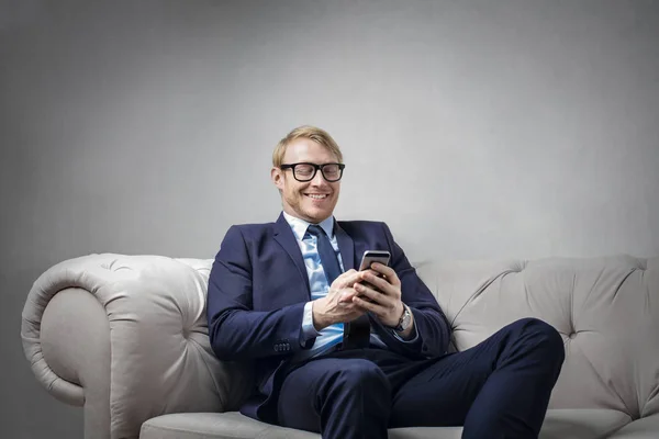 Empresario con teléfono sentado en el sofá — Foto de Stock