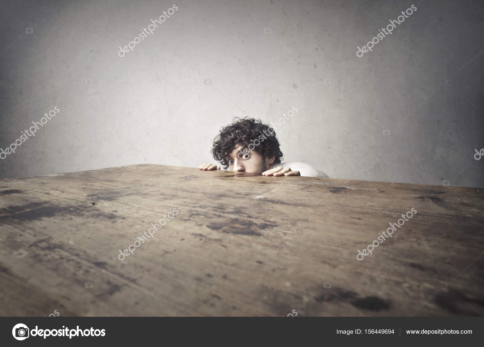 Scared man hiding behind wood table Stock Photo by ©olly18 156449694