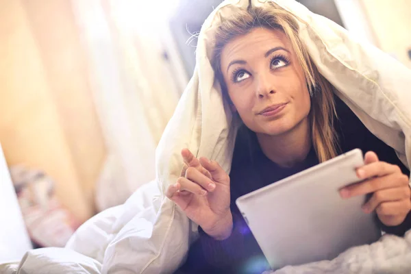 Mulher loira estudando sob os cobertores — Fotografia de Stock