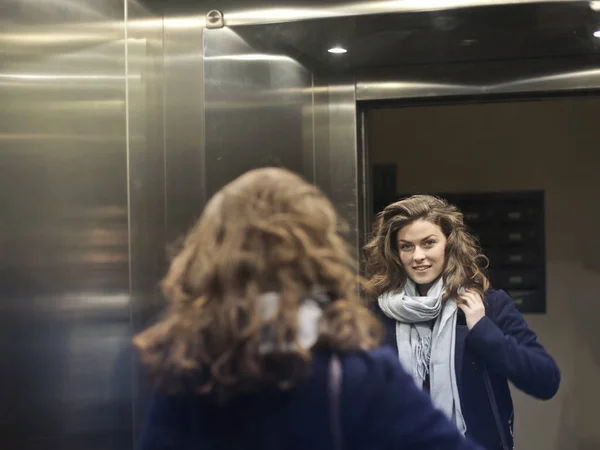 Young brunette woman looking into mirror — Stock Photo, Image