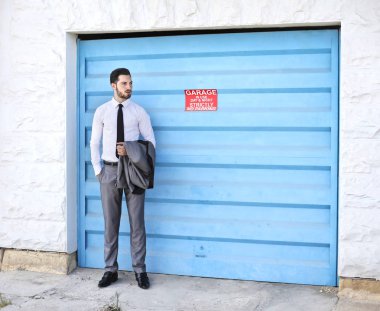 Businessman standing in front of blue garage  clipart