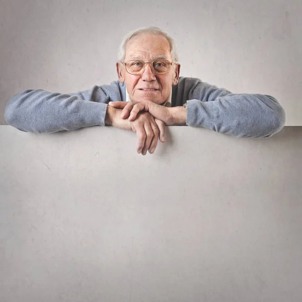 Starý muž opíraje se o bílou tabuli — Stock fotografie
