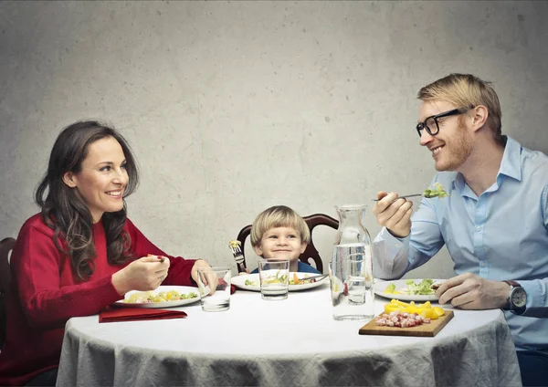 Семья из 3 человек ест за столом — стоковое фото