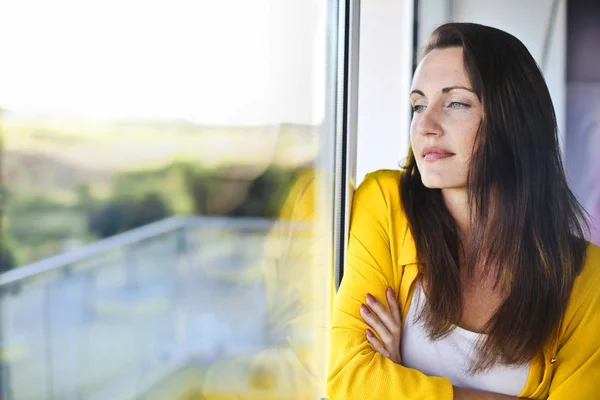 Vrouw op zoek uit raam — Stockfoto