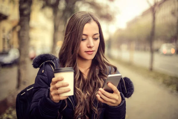 Mladá bruneta žena při pohledu na její telefon — Stock fotografie
