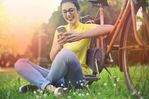 Brünette Frau sitzt neben Fahrrad — Stockfoto