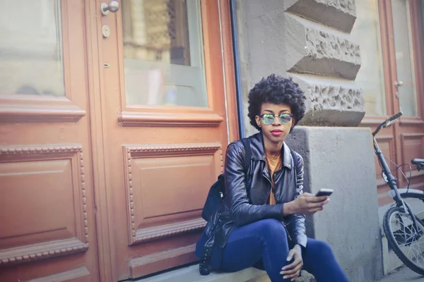 Mladá černá žena sedí u dveří — Stock fotografie