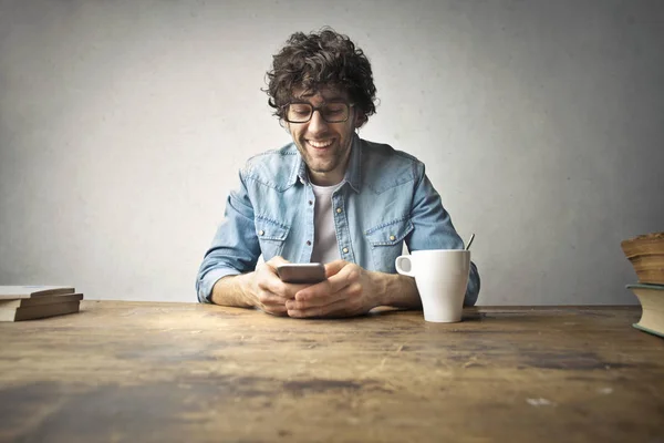 Человек в очках смотрит в телефон — стоковое фото