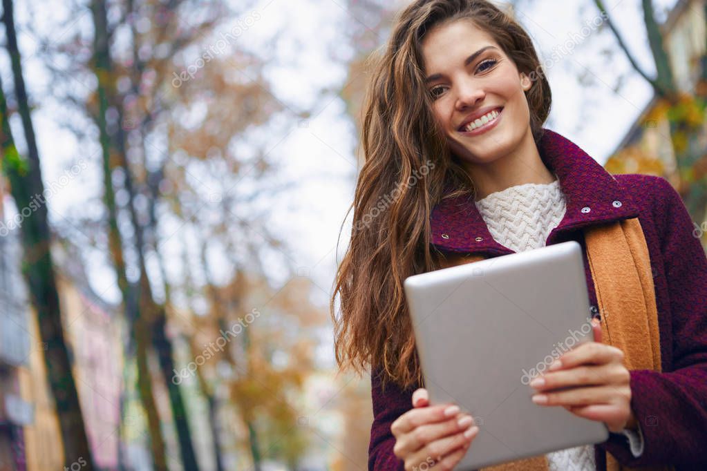 Brunette woman with tablet outside