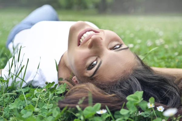 Bruneta žena ležící v trávě — Stock fotografie