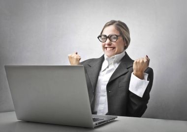Bir dizüstü bilgisayar önünde exulting Buisnesswoman